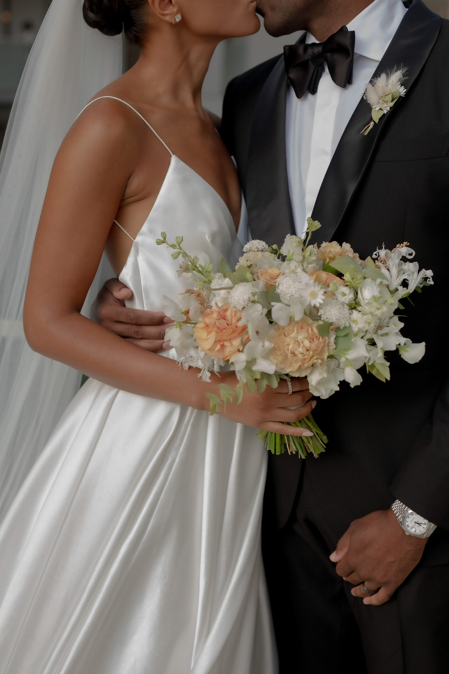 Luxury Tuscany wedding bride holding a bouquet and kissing the groom