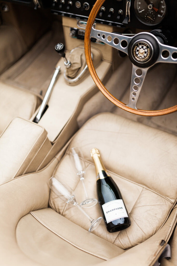 Convertible car with champagne bottle and two glasses prepared for a luxury Tuscany wedding celebration